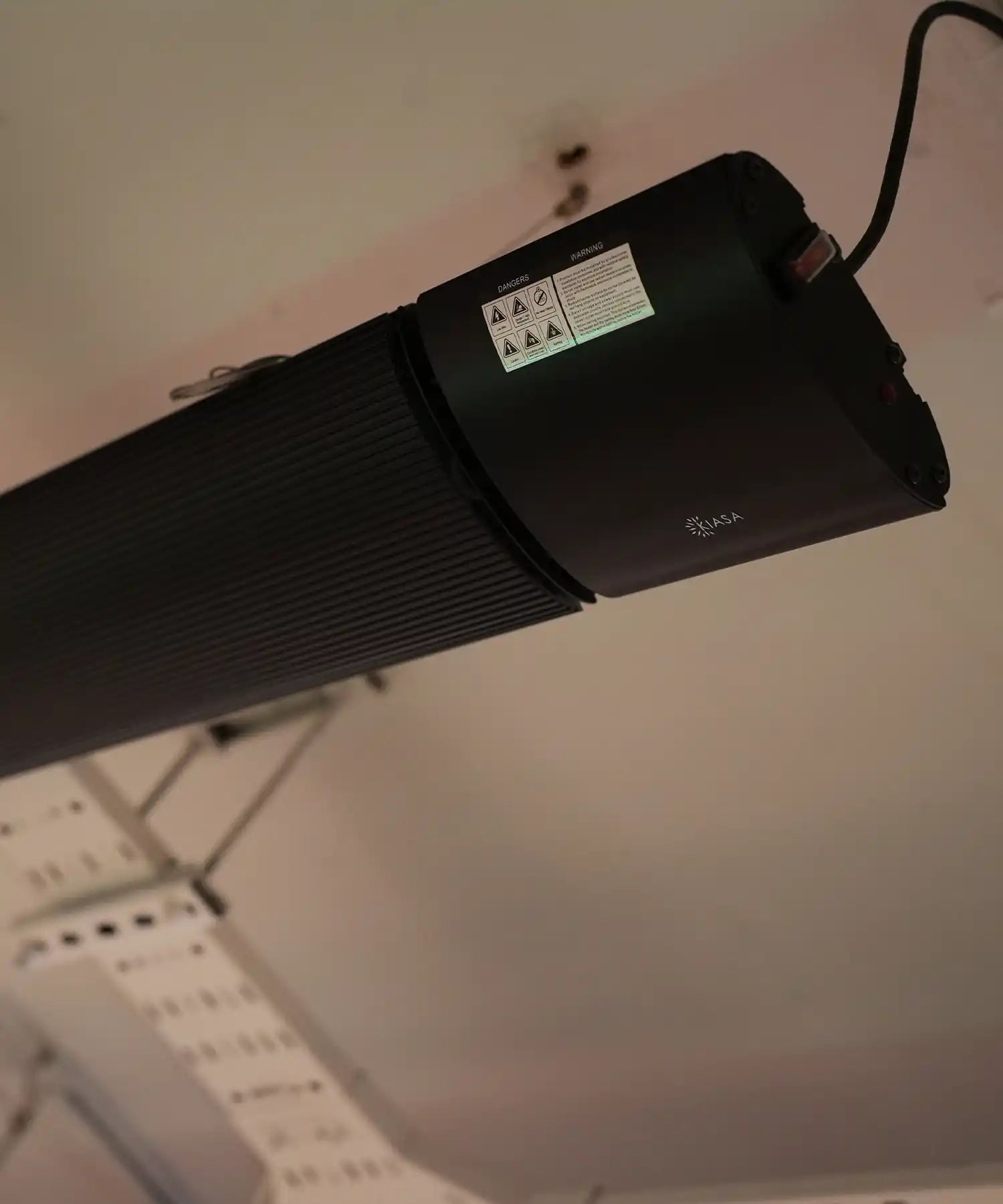 Close-up of a ceiling-mounted IKON infrared heater bar by KIASA, showcasing its slim cylindrical design and discreet professional installation.