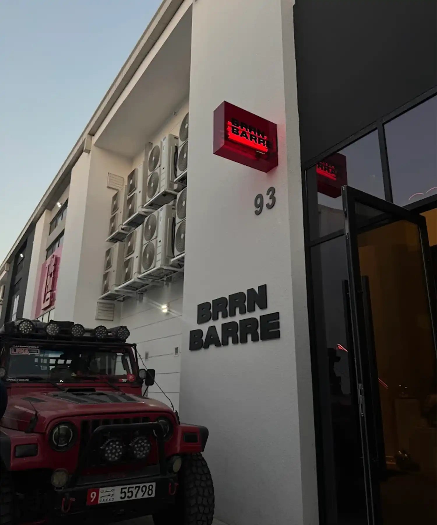 Red vehicle parked in front of a building with 'Barn Barre' branding.