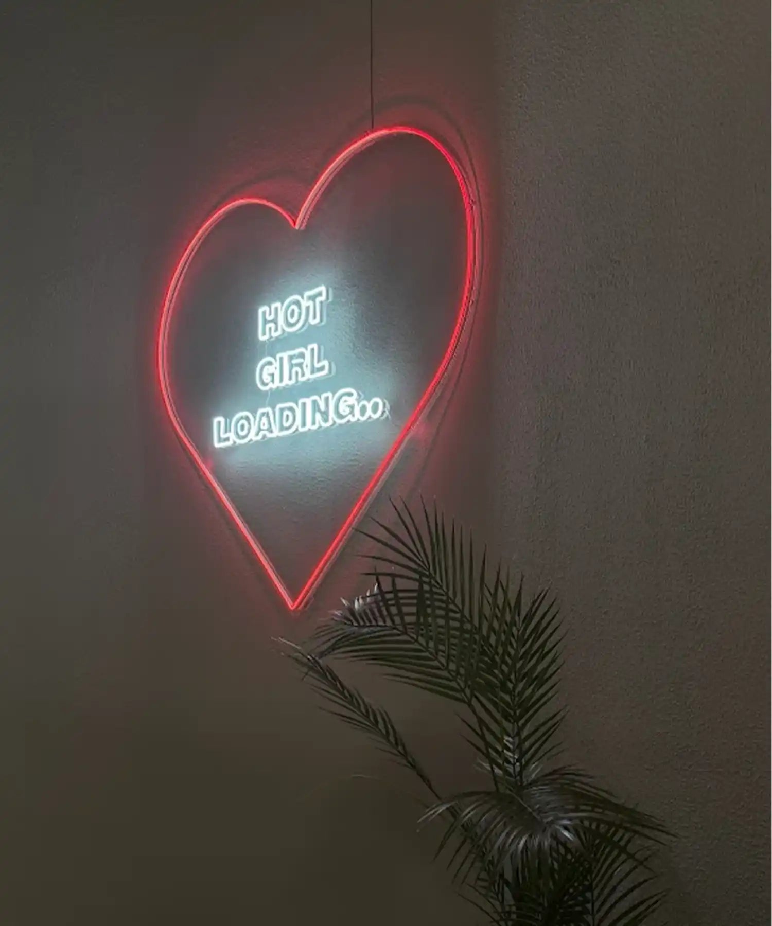 Neon sign reading ‘Hot Girl Loading’ on a wall at BRRN BARRE Dubai with red glow and visible infrared heater bars above, studio prepping for class