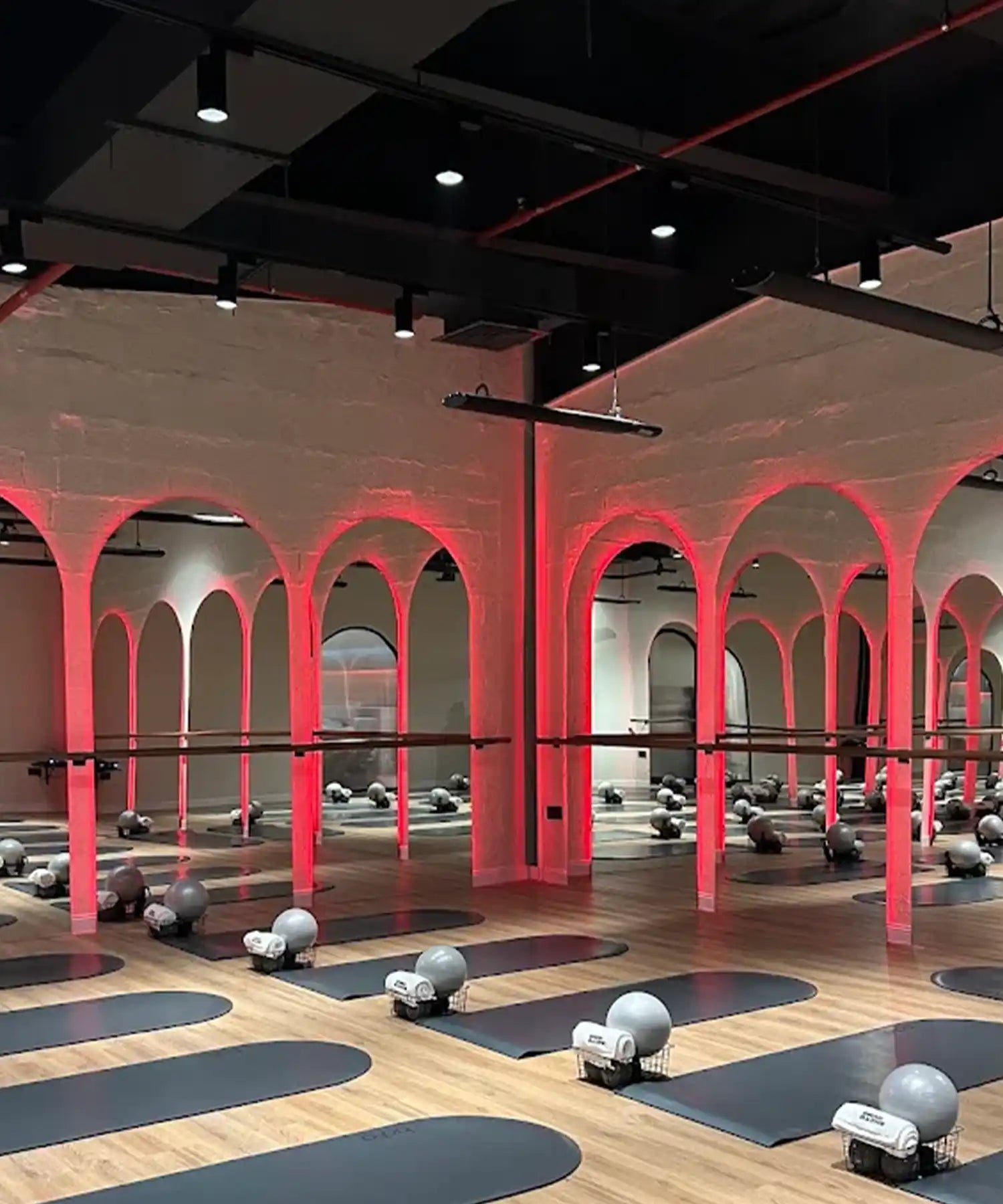 BRRN BARRE Dubai hot-room interior with rows of mats and equipment, red-accent lighting, and IKON infrared heater bars mounted overhead in a fitness studio.