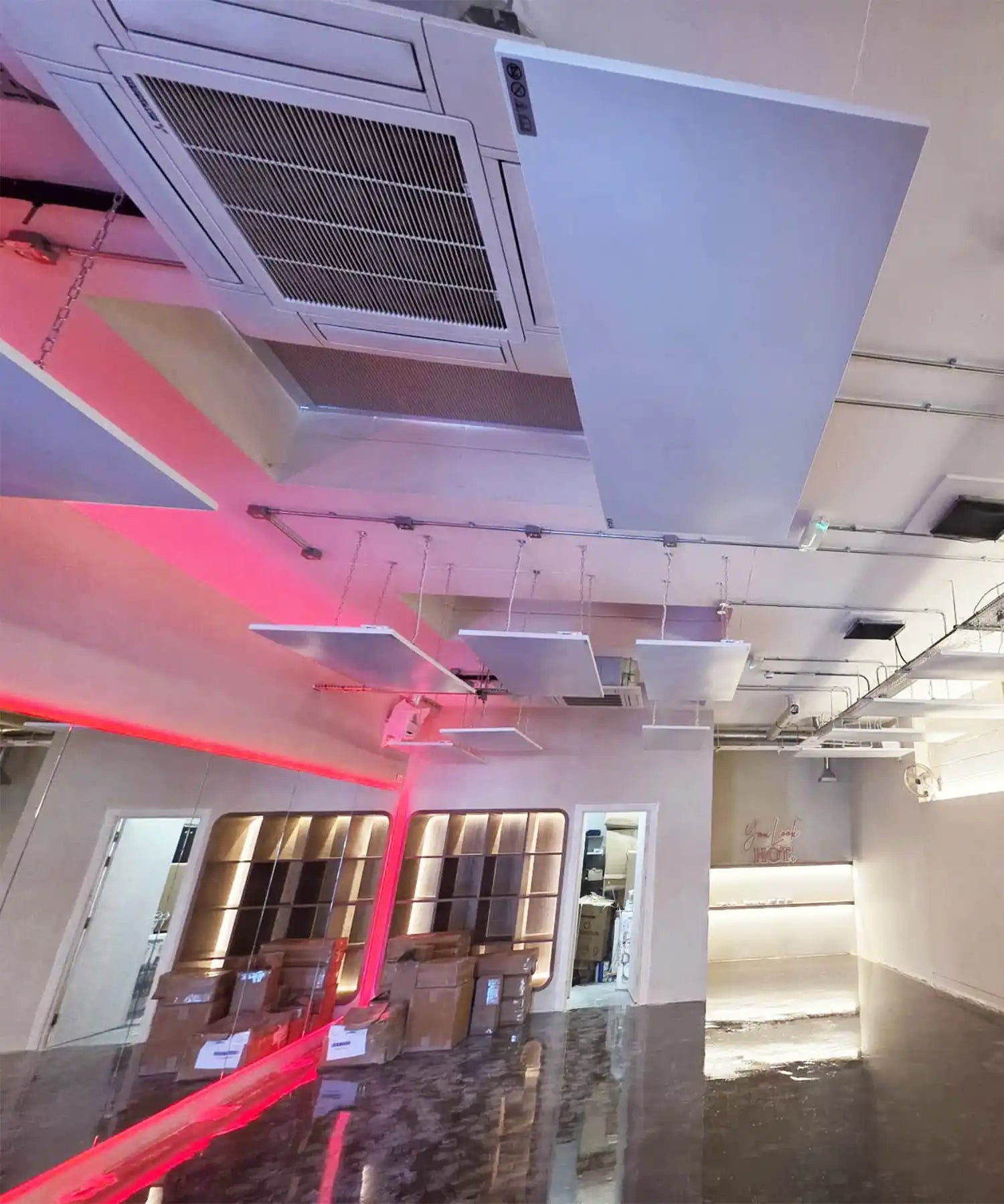 Interior of YOURS Studio London showing ceiling-mounted infrared heating panels above the workout area, red accent-lighting and minimalist barres.