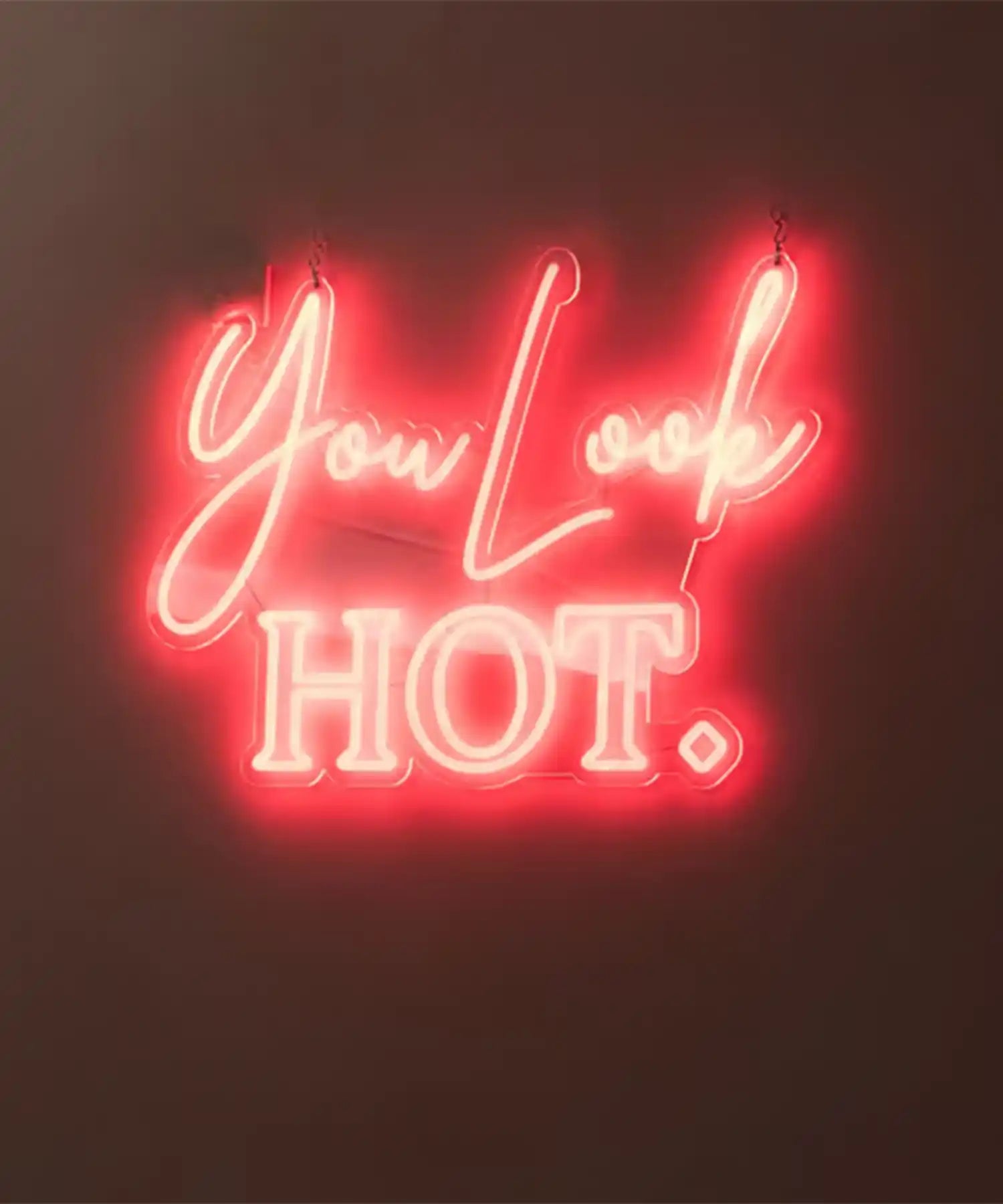 Neon sign reading ‘You Look HOT.’ inside YOURS Studio London, with visible infrared heater bars or panels above, creating a warm studio ambiance.