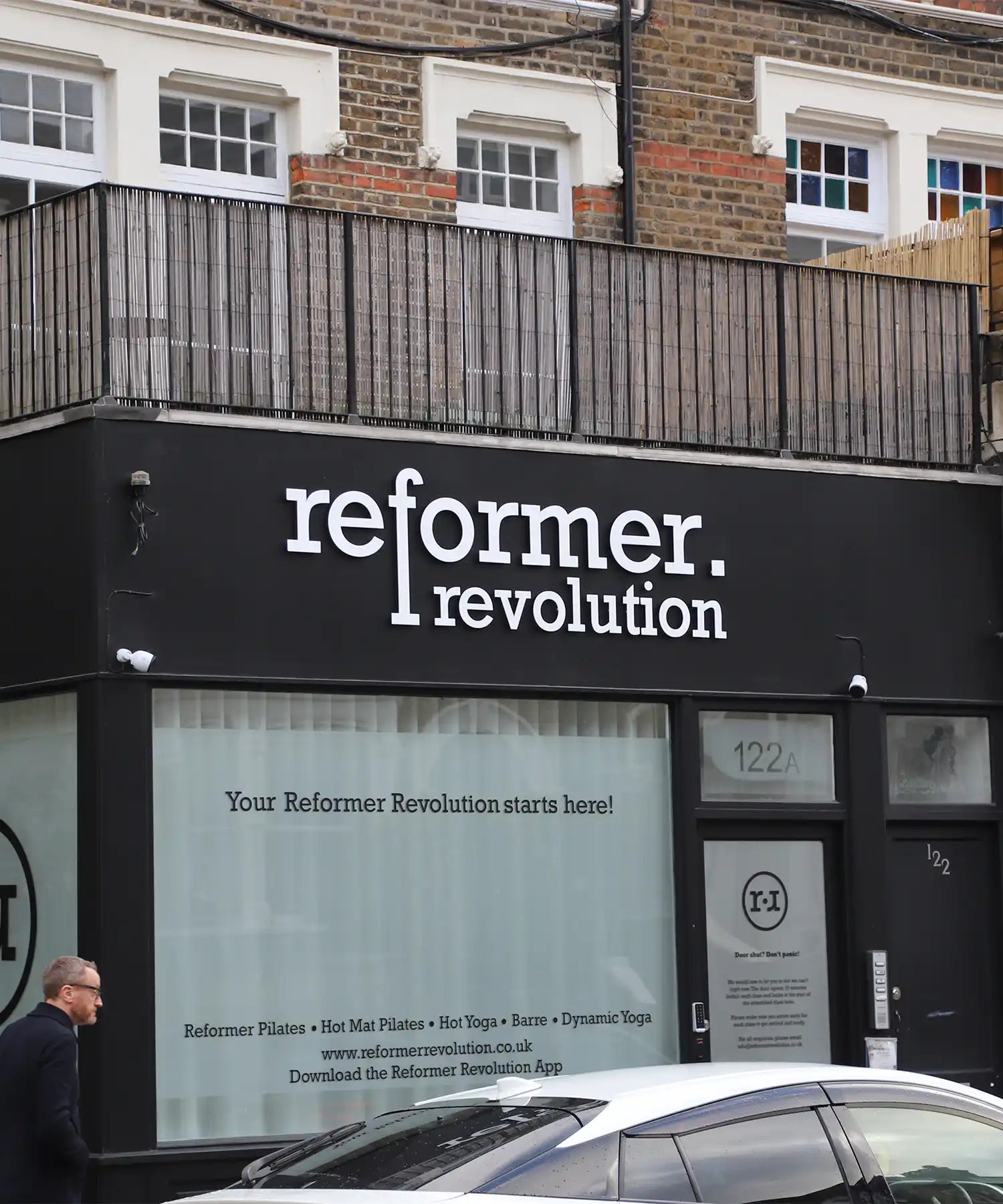 Front entrance of Reformer Revolution studio in Northwest London, showing the black storefront signage promoting Reformer Pilates, Hot Yoga and Barre.