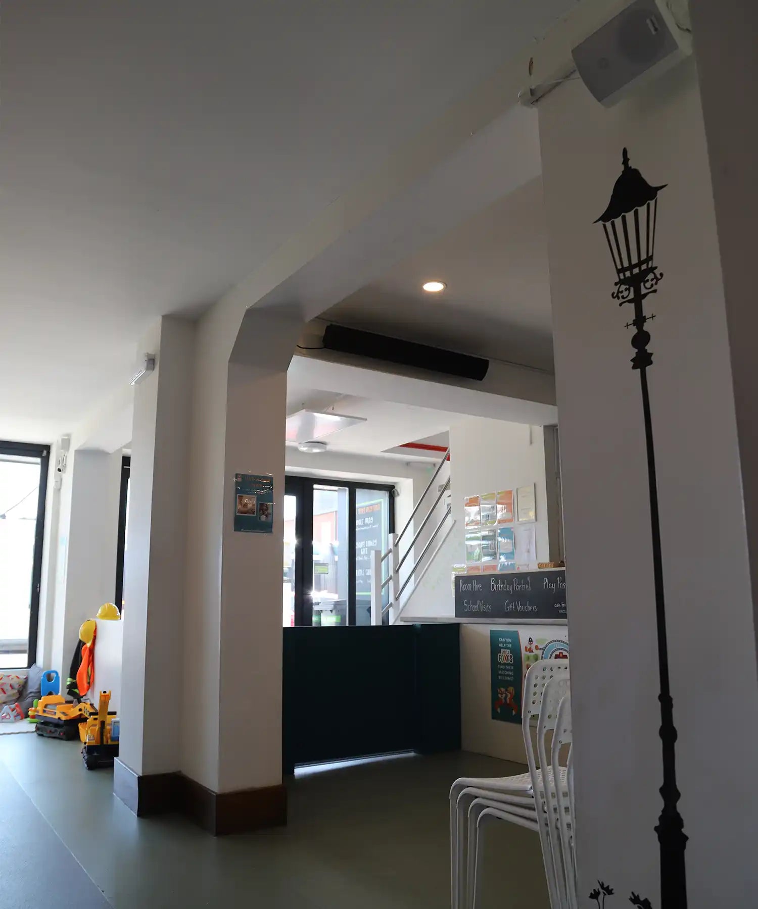 Wide shot of Little Foxes Play Town's entrance and play area, showing both infrared panel heaters and a black heater bar integrated discreetly into the ceiling structure.