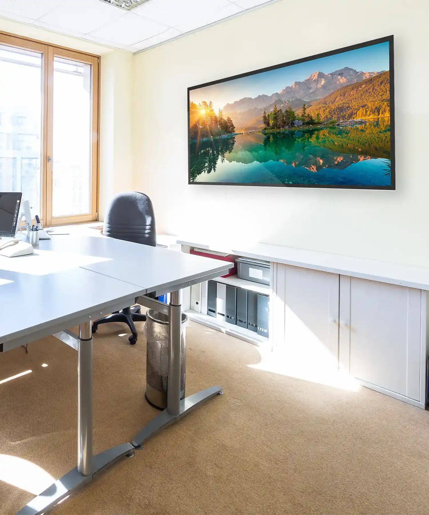 Wide panoramic landscape infrared panel heater displaying a serene lake and mountain sunrise, wall-mounted in a modern office space