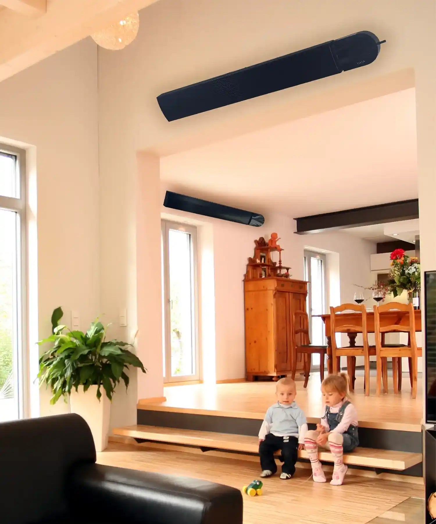 Two KIASA black heater bars mounted in a bright, open-plan family living room where two young children sit on a step.