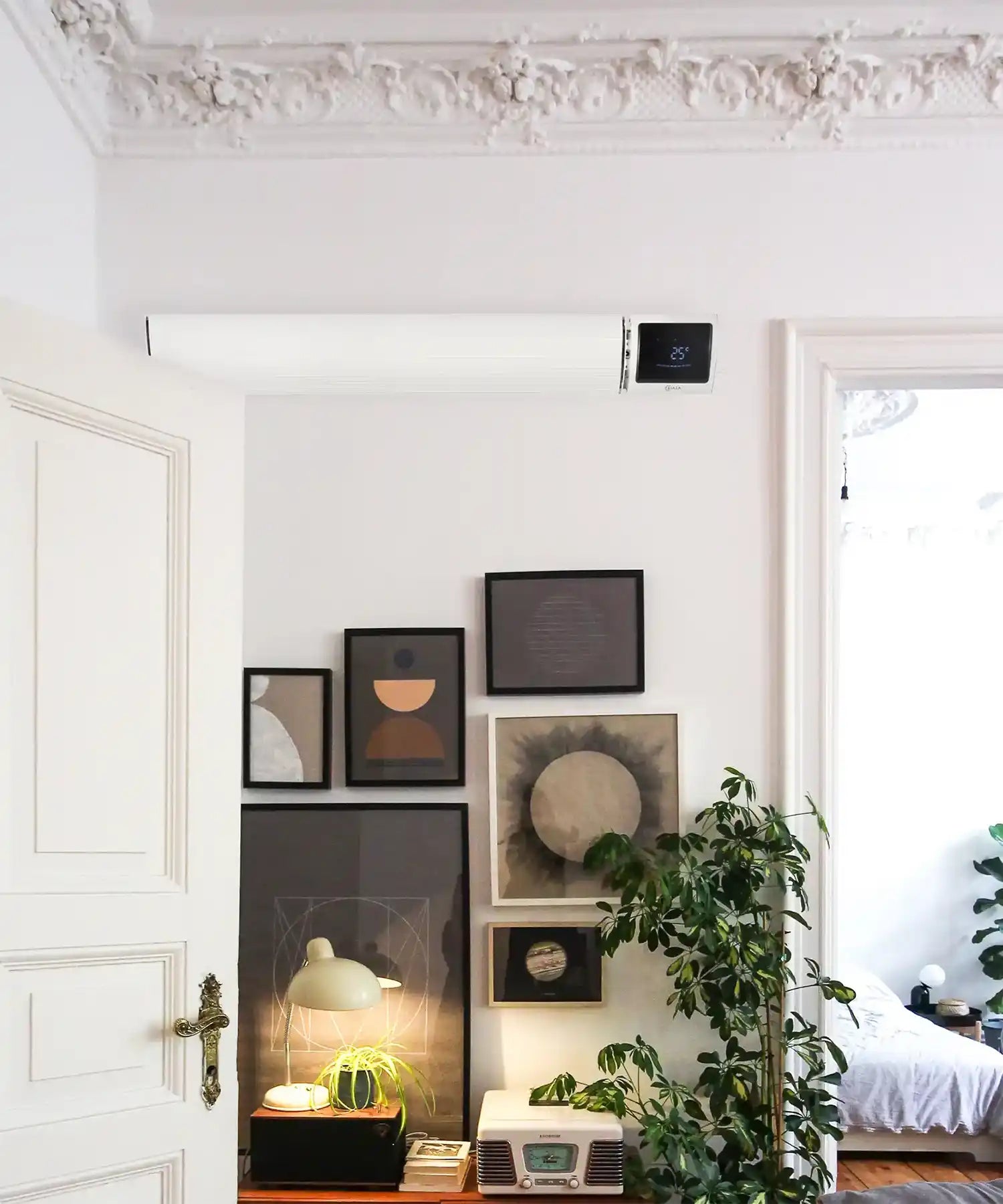 White Kiasa IKON infrared heater mounted above framed wall art in a chic apartment interior.