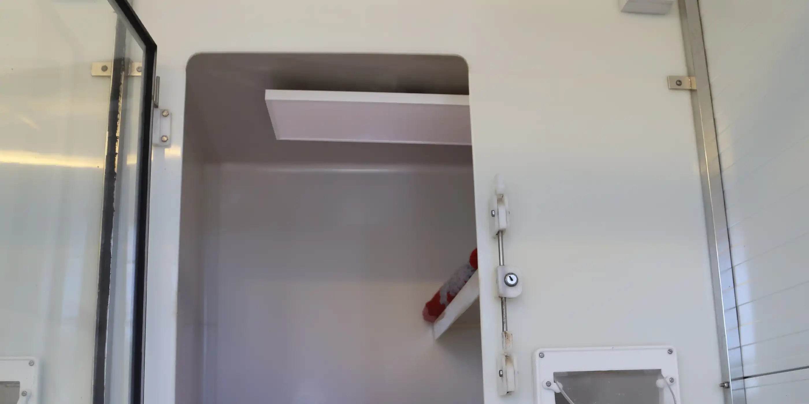 Ceiling-mounted KIASA 180W infrared heating panel inside an unoccupied cattery pen at an animal shelter, showing safe and space-efficient heating setup.