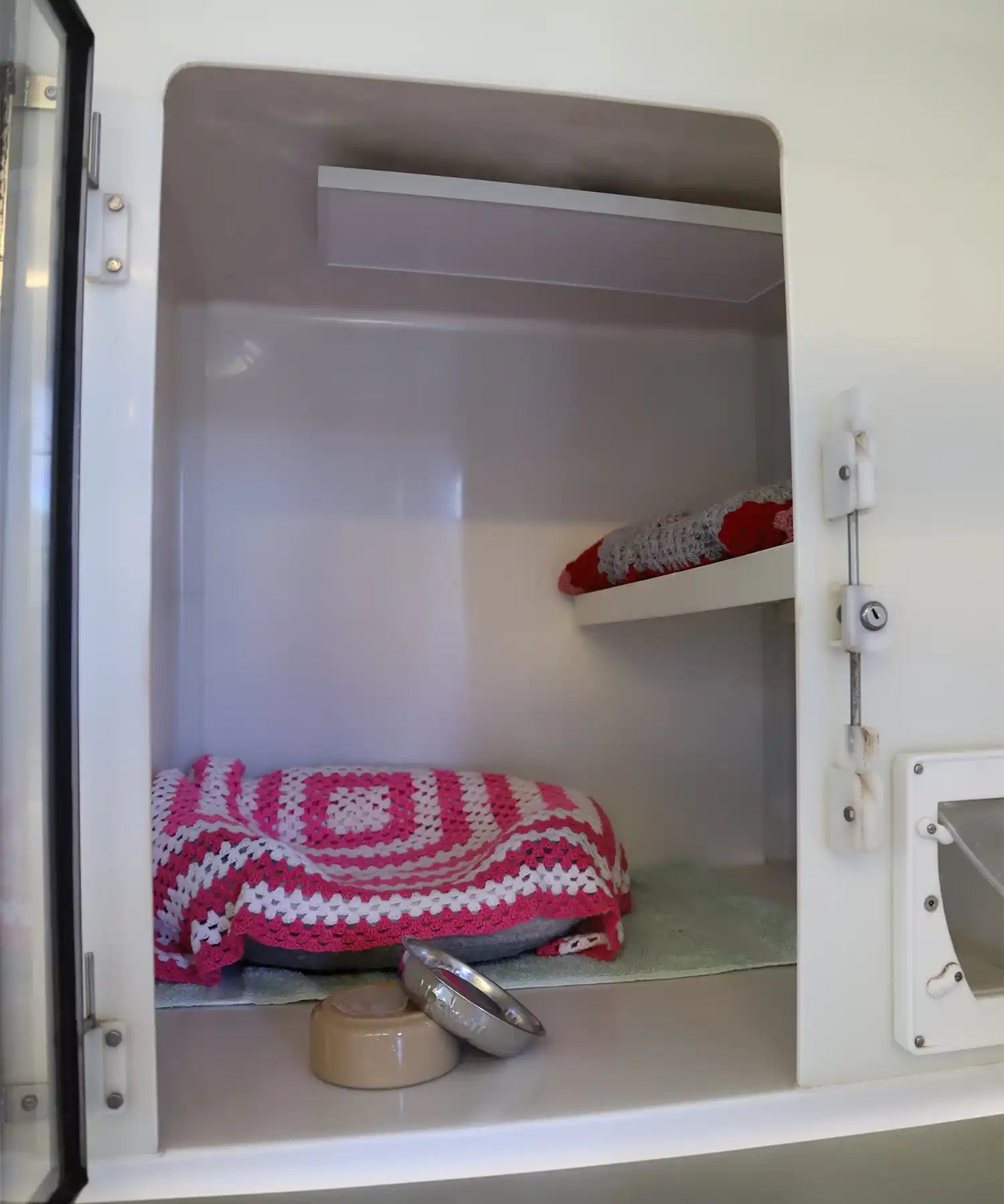 Interior of a cattery sleeping pod with two colourful crocheted beds and a ceiling-mounted KIASA infrared panel for gentle radiant heating.