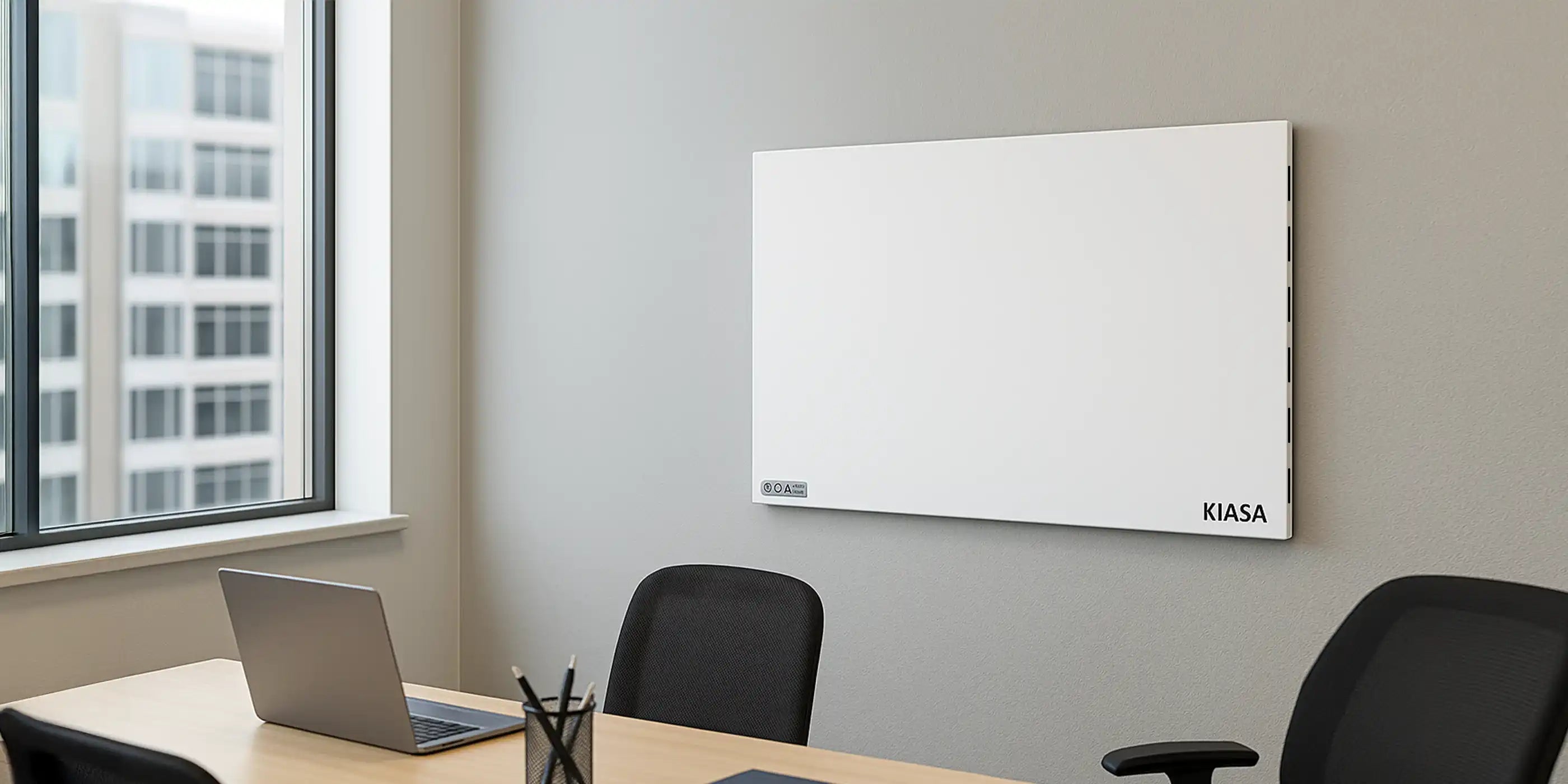 Kiasa Kore Hybrid Heater wall-mounted in a contemporary office with large windows and a laptop on desk