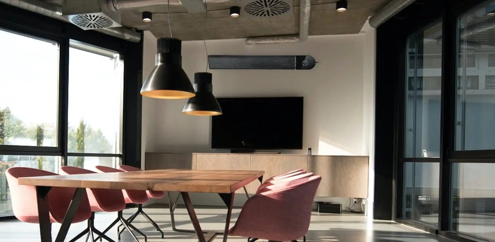 Black KIASA Smart Infrared Heater Bar wall-mounted in a modern glass-walled office meeting room with industrial ceiling, wooden table, and pink chairs.