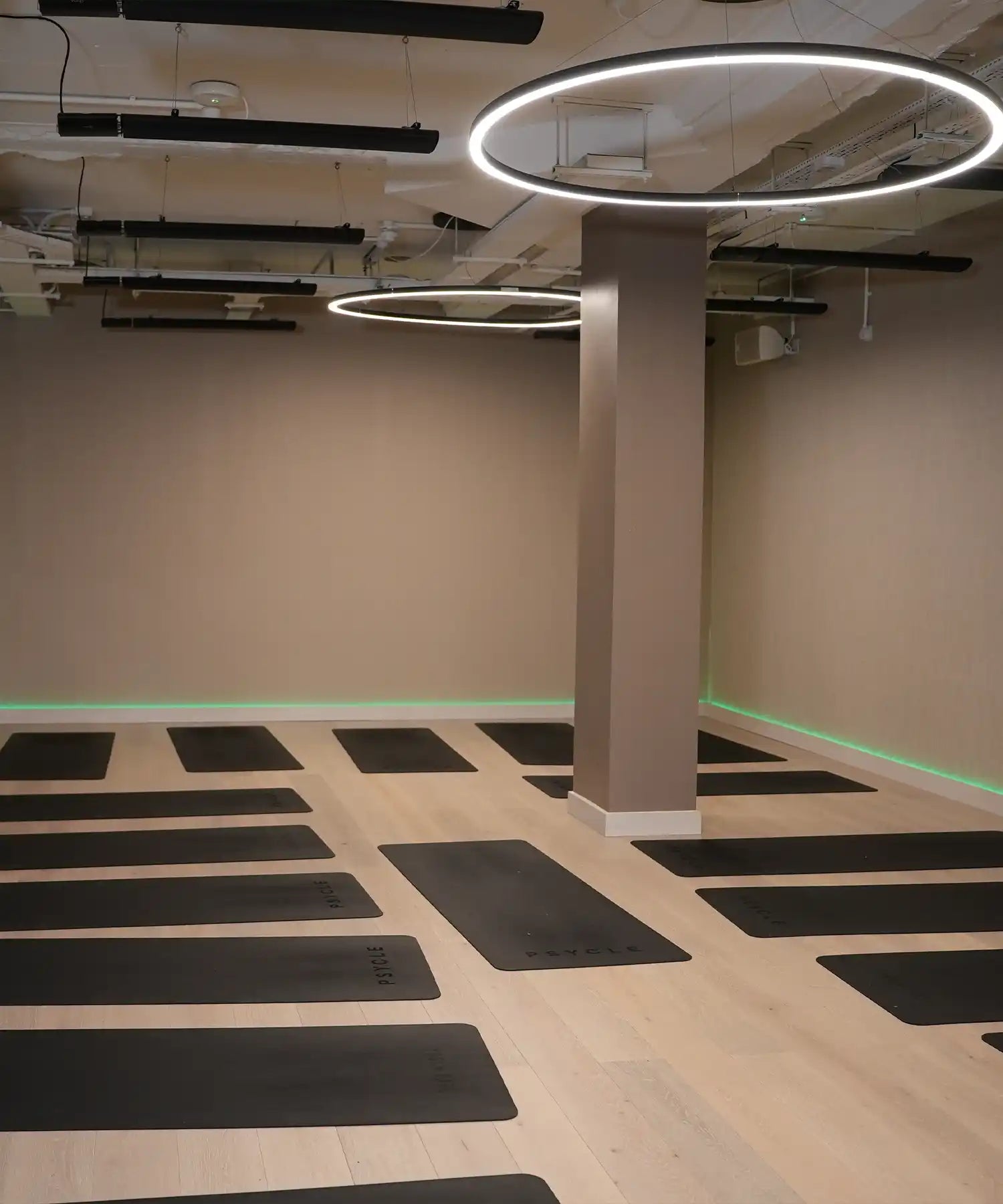 Contemporary yoga studio with warm lighting, organised props and ceiling-mounted IKON infrared heater bars delivering consistent heat throughout the room.