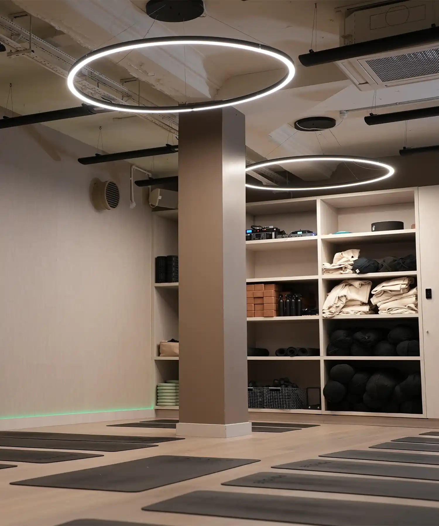 Modern hot yoga studio with neatly arranged mats, circular ceiling lights, and ceiling-mounted IKON infrared heater bars providing silent, even radiant heat.