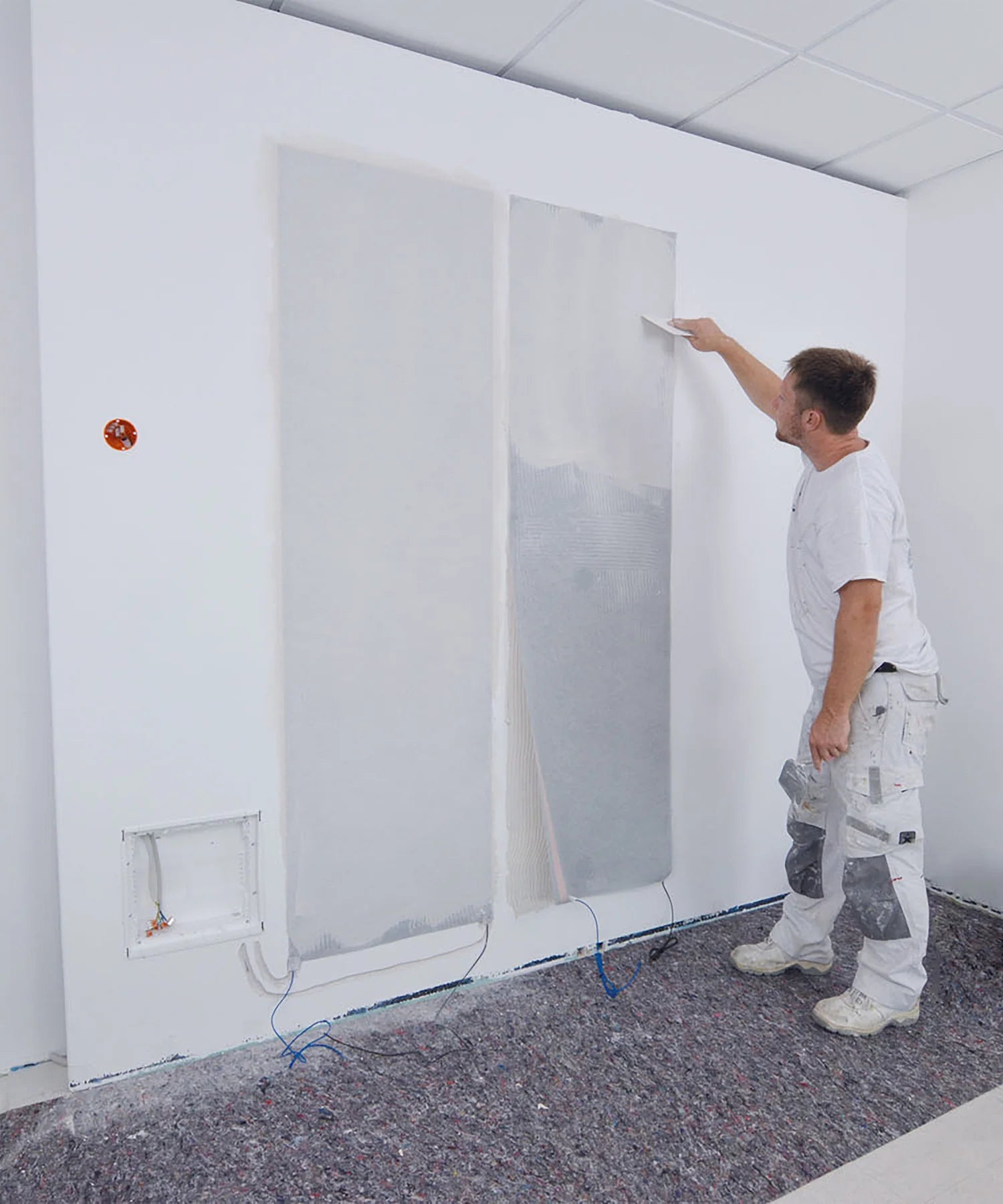 A man doing putty and painting on wall