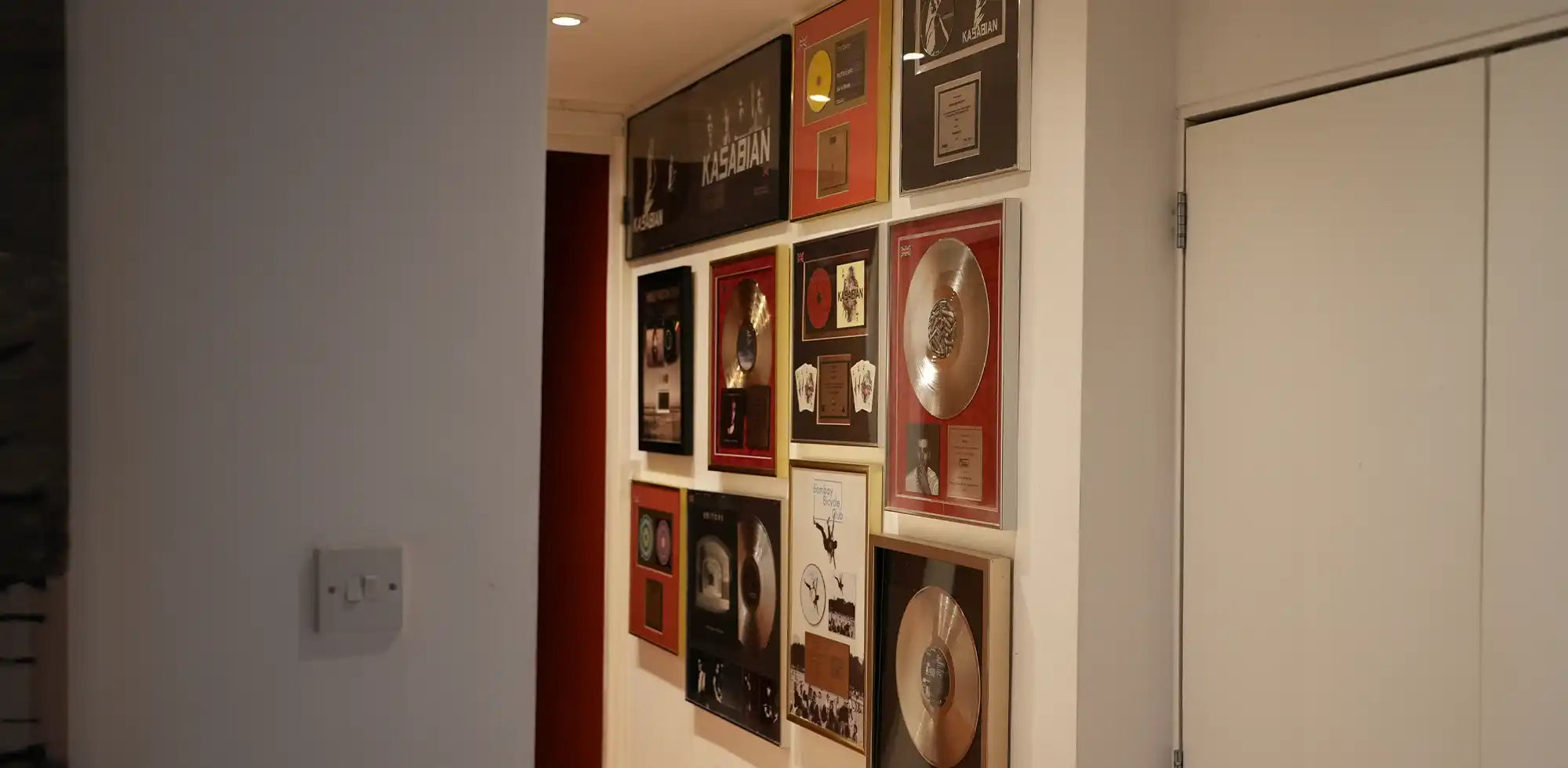 Hallway at an independent recording studio displaying framed music awards with discreet ceiling-mounted infrared heating panels