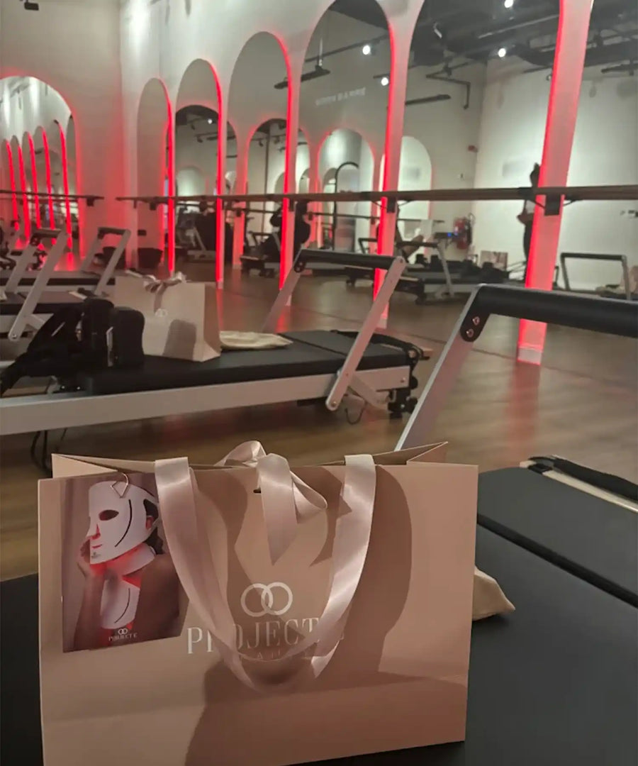 Interior of BRRN BARRE Dubai studio with rows of yoga/barre mats, red-highlighted pillars, overhead IKON infrared heater bars, and a warm-toned environment suited for hot workouts.