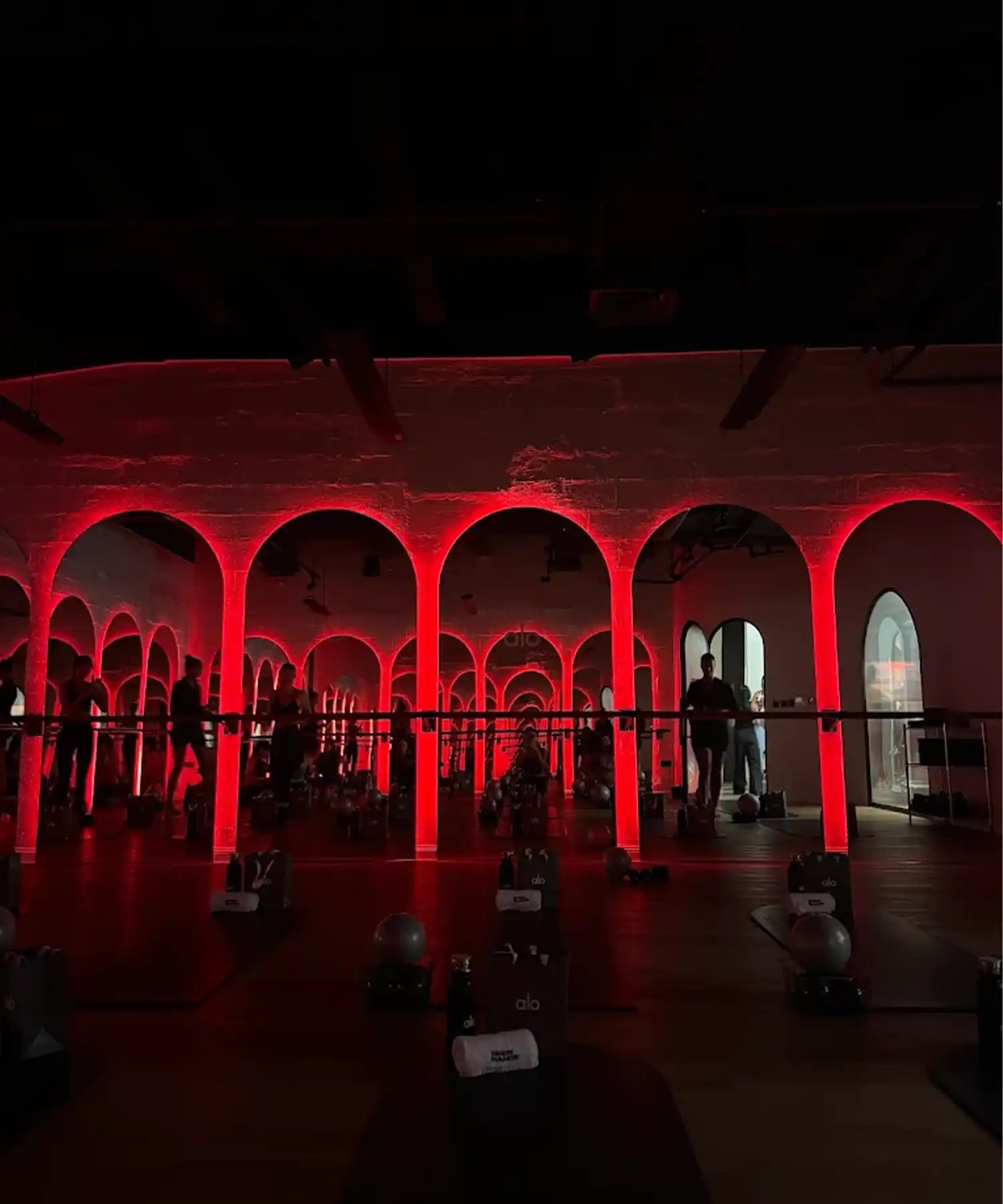 Women doing barre class in a hot-room studio at BRRN BARRE Dubai, with visible IR heater bars mounted overhead and warm ambient lighting.