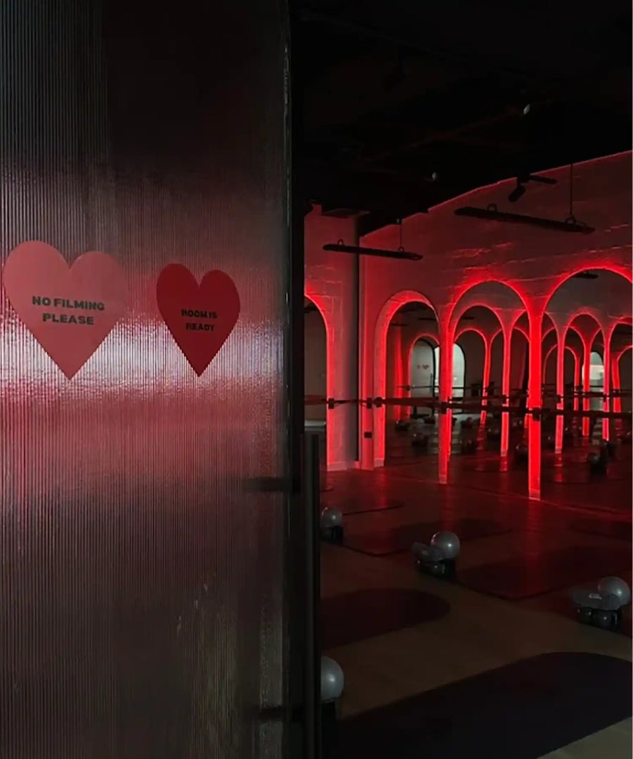 Exterior entrance of BRRN BARRE Dubai in Goshi Warehouse City Al Quoz, showing industrial façade and overhead array of IKON infrared heater bars visible through windows.