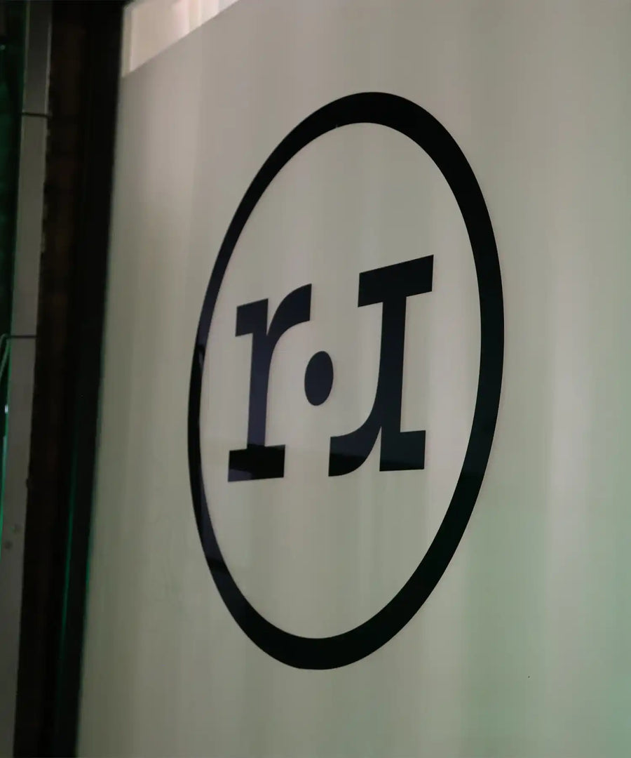 Close-up of the Reformer Revolution studio logo printed on the front window, featuring the minimalist circular “r•r” design