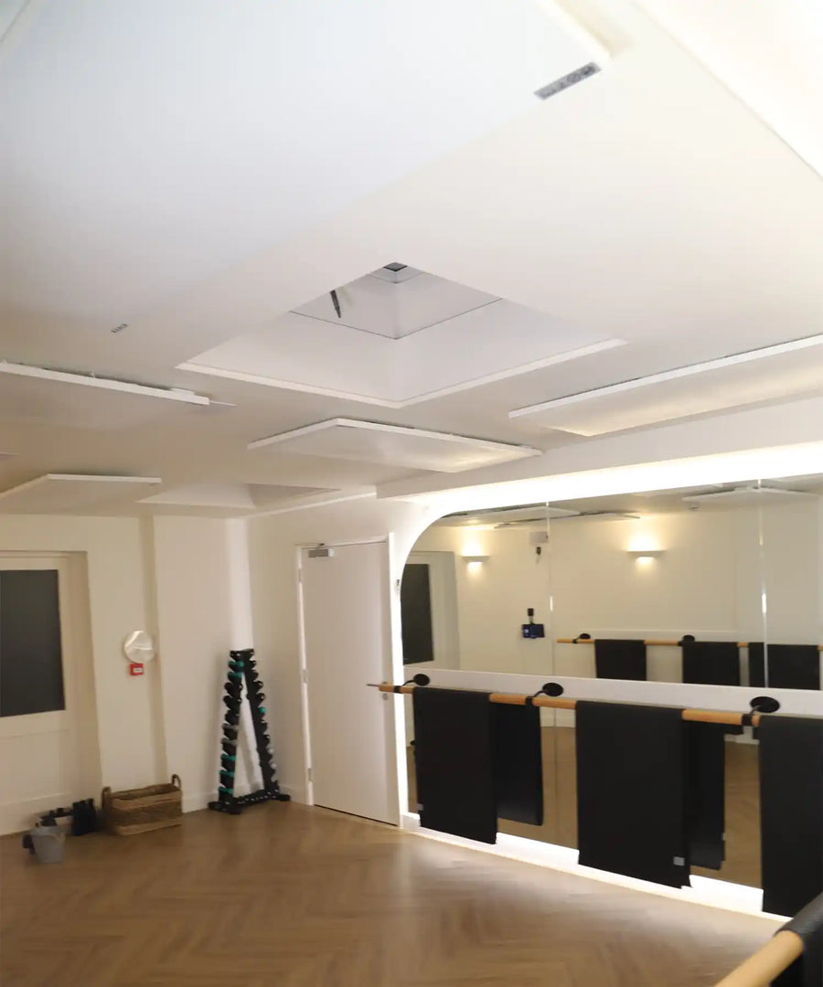 Barre studio interior at Reformer Revolution featuring mirrored walls, ballet barres and multiple KIASA KORE Balance infrared heating panels mounted across the ceiling for even hot-studio heat distribution.