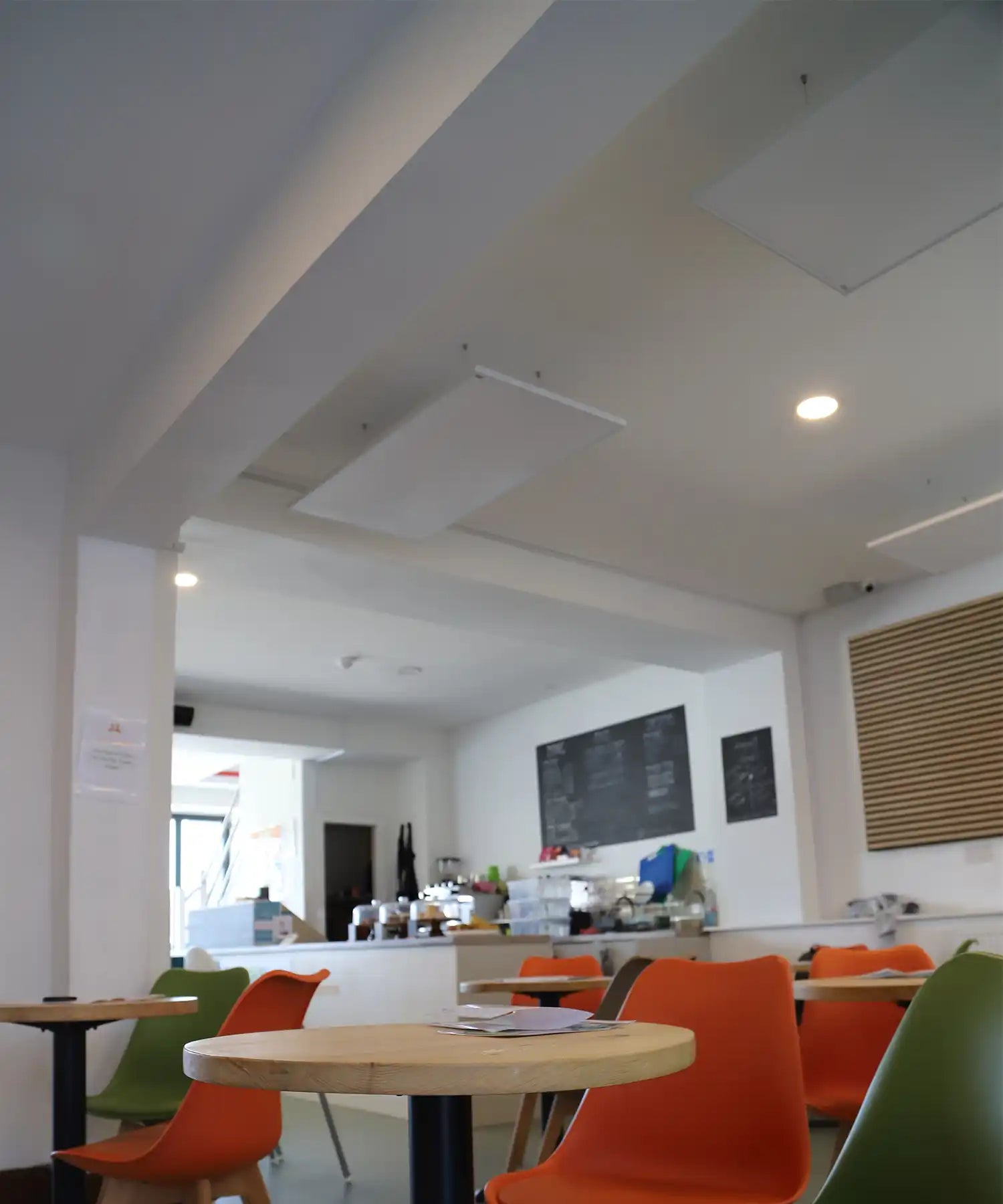 Café seating area at Little Foxes Play Town with orange and green chairs, and KIASA infrared panels mounted overhead for ambient heating.

