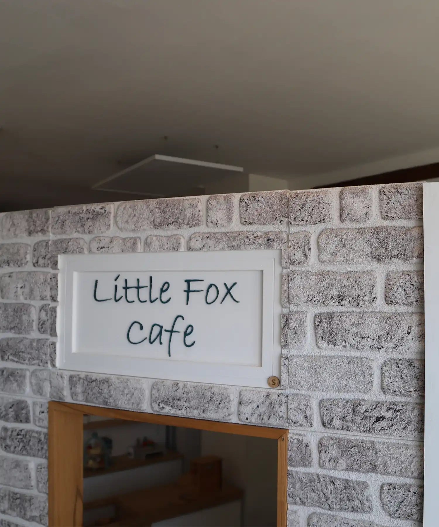 Entrance to the Little Fox Café at Little Foxes Play Town, with faux brick walls and an infrared heating panel mounted discreetly on the ceiling.

