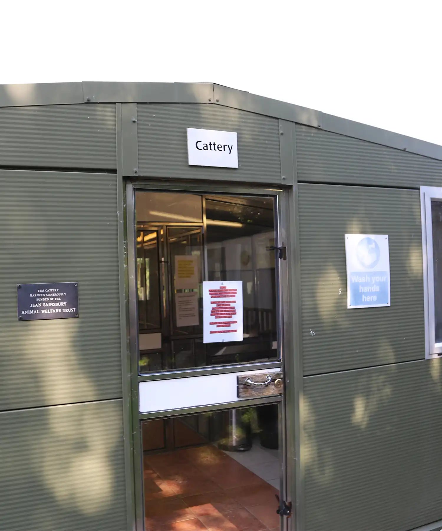 Exterior of the All Creatures Great and Small cattery building, showing the entrance sign and animal welfare notices.

