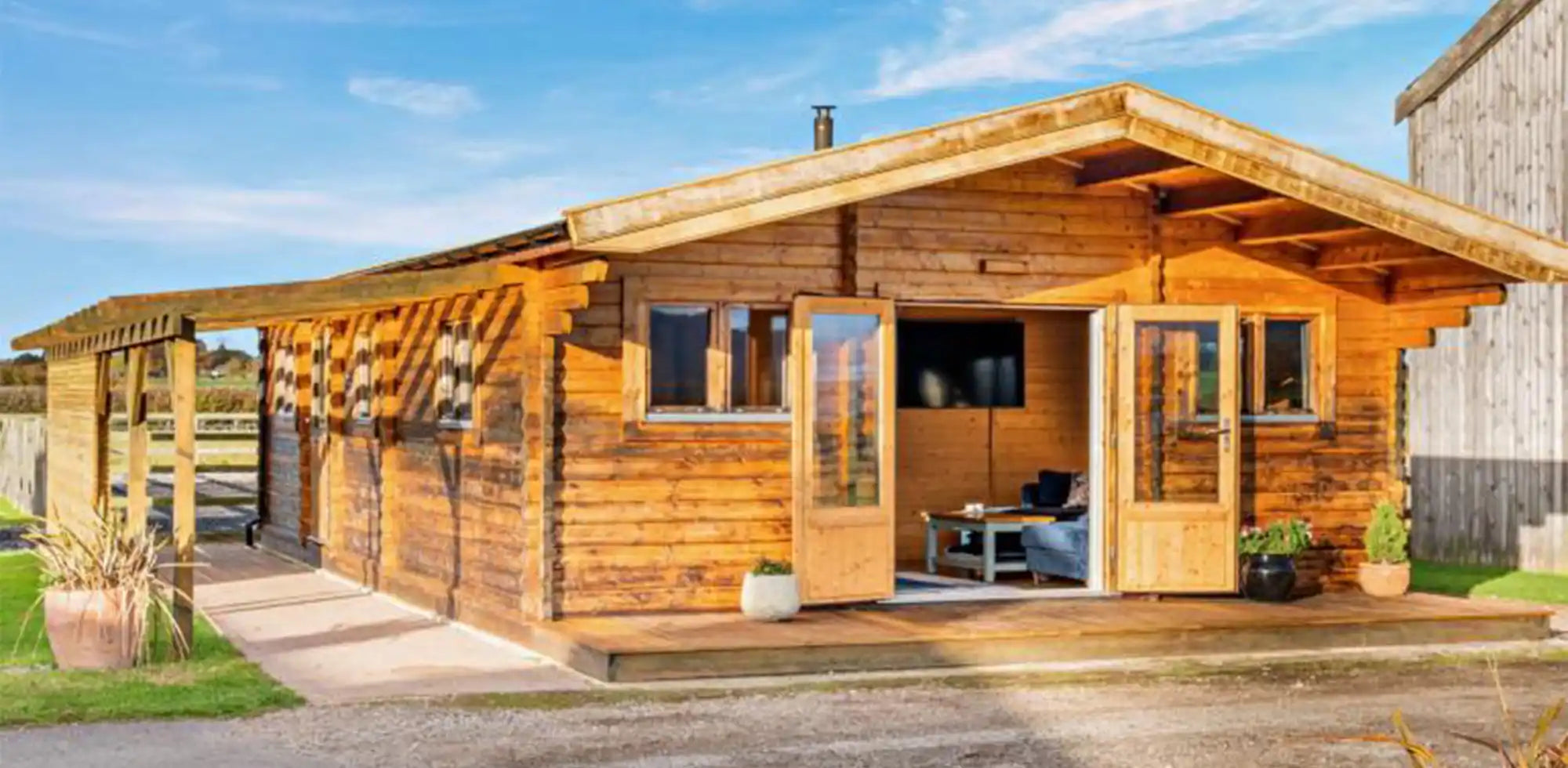 Exterior front view of Bluebell Lodge holiday rental, wooden cabin structure with open doors leading into the living area.
