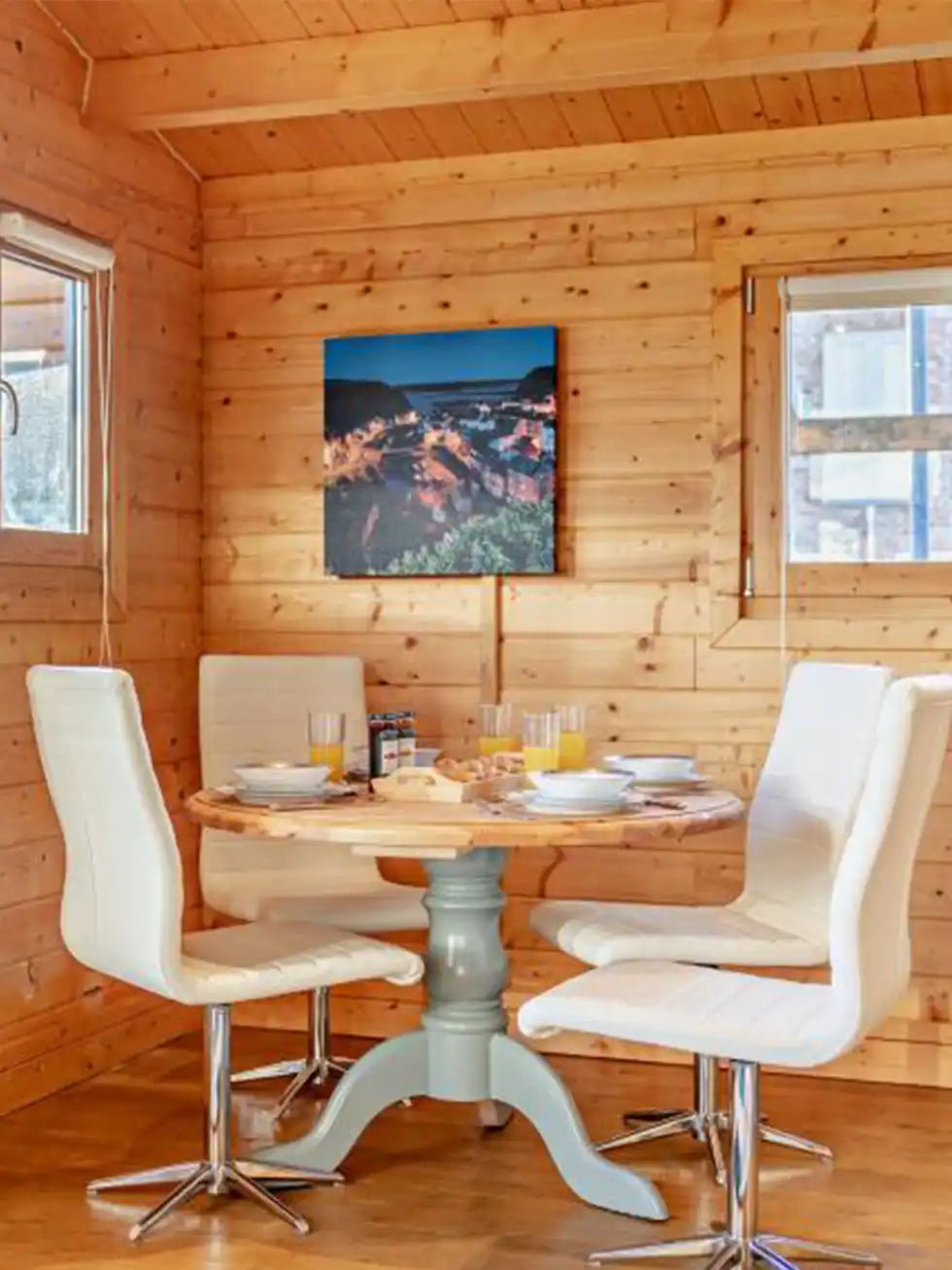 Custom infrared canvas heater panel installed in dining area of wooden lodge, above round dining table with white chairs.