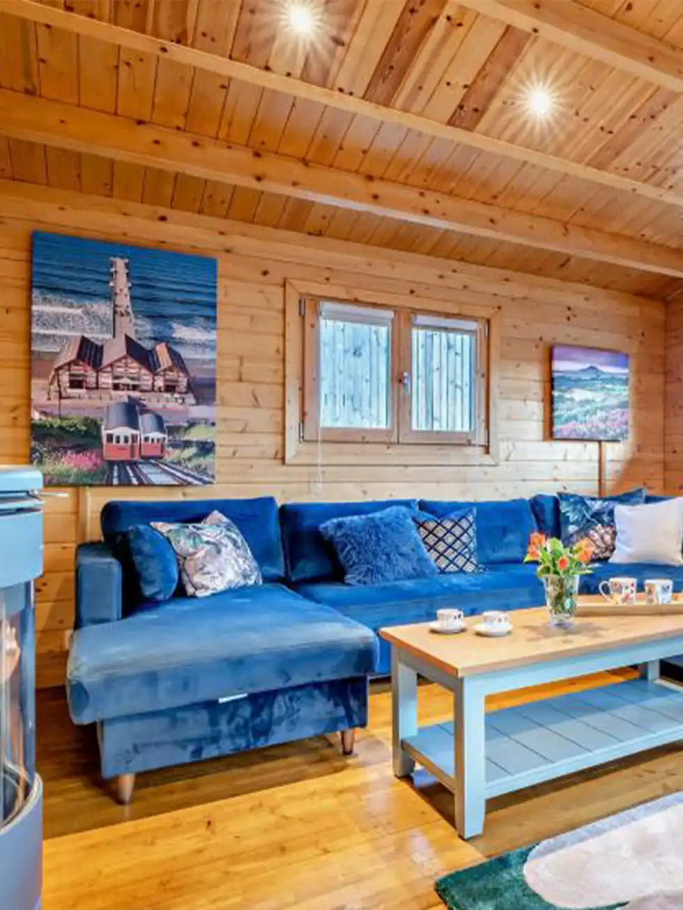 Custom infrared canvas heater panel in Bluebell Lodge living room, mounted on wooden panelled wall above blue sofa