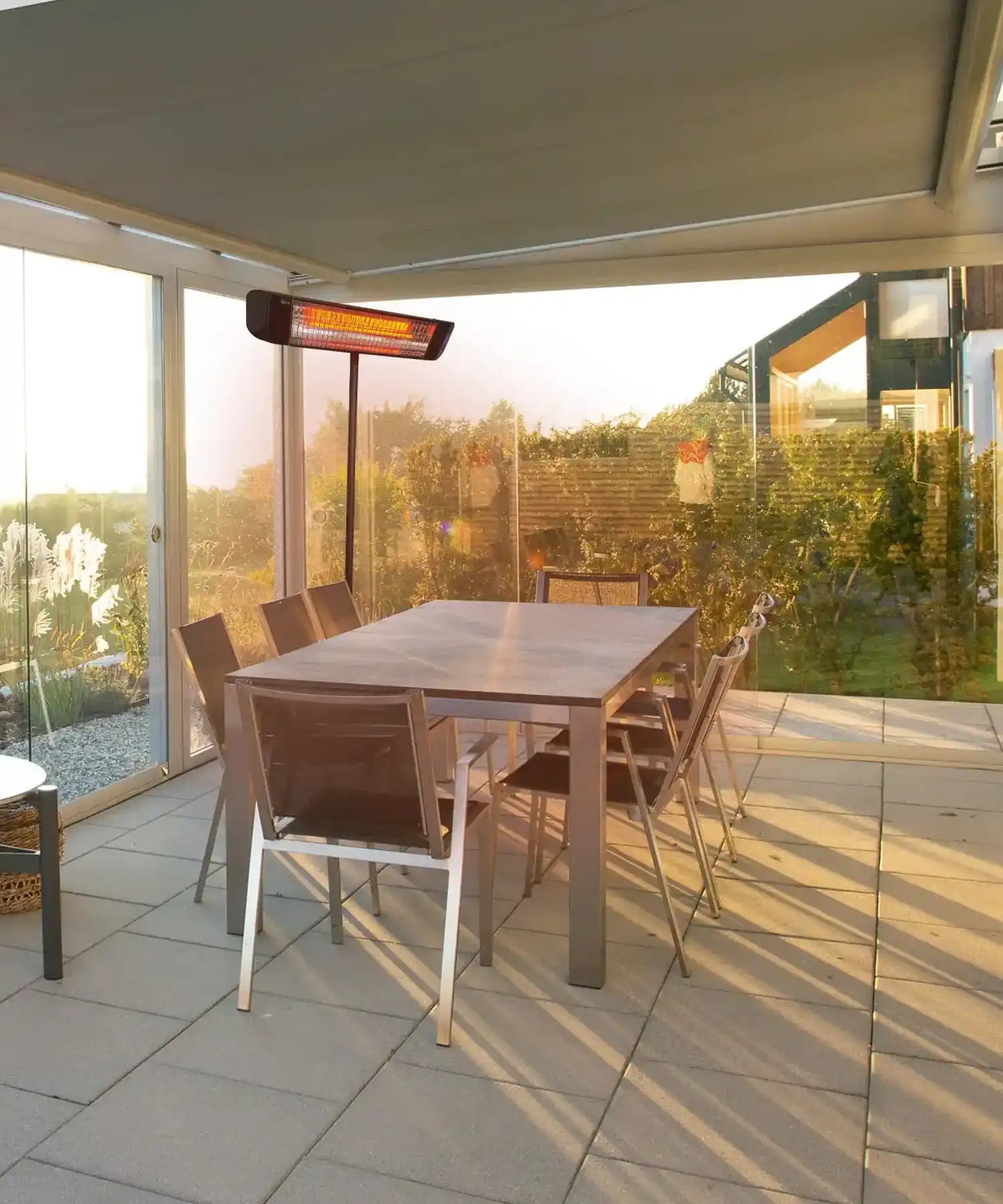 Freestanding infrared patio heater heating outdoor garden dining area under covered terrace.